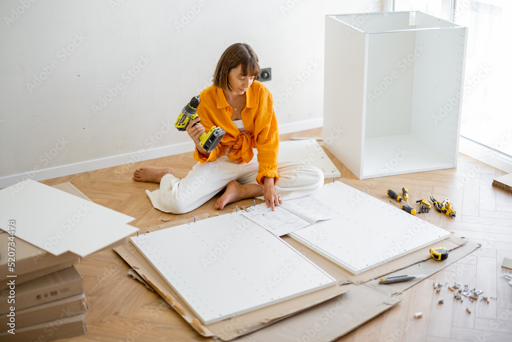 Young woman assembles furniture by herself while renovating her new apartment. DIY and house improve