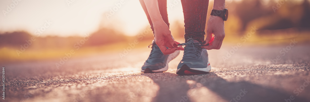 运动型女性在开始跑步前系鞋带。