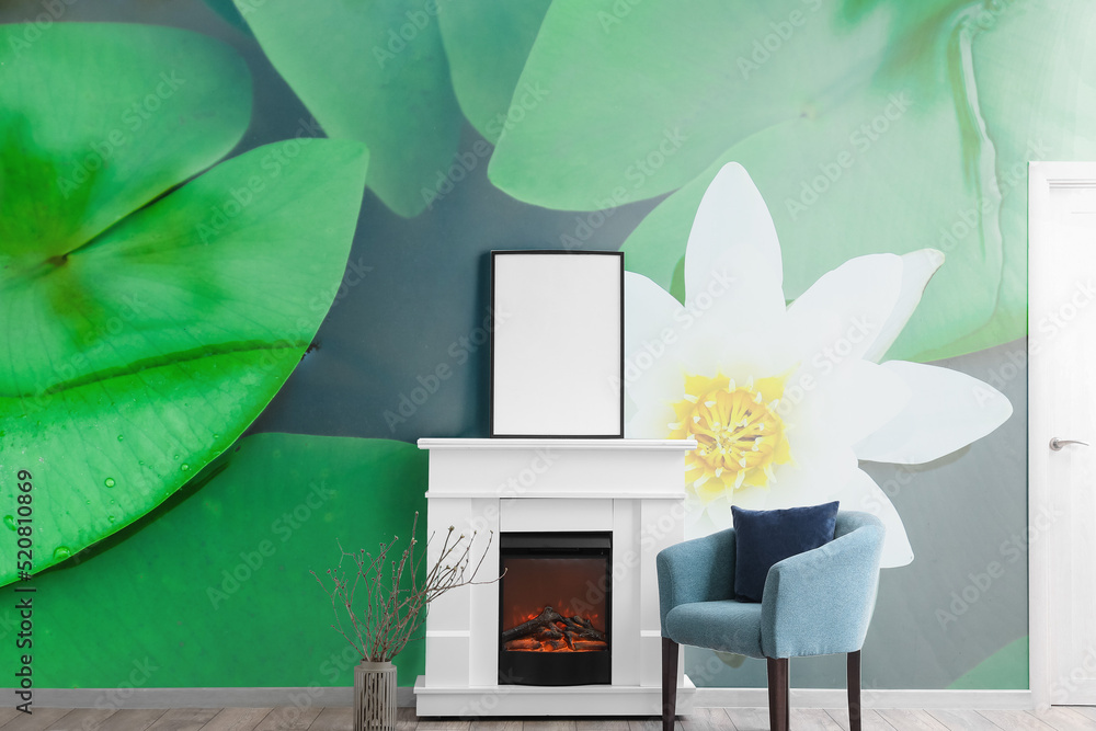 Interior of light living room with fireplace, armchair and wall with print of water lily
