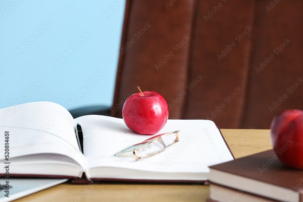 红苹果配眼镜，教室桌子上放着书，特写