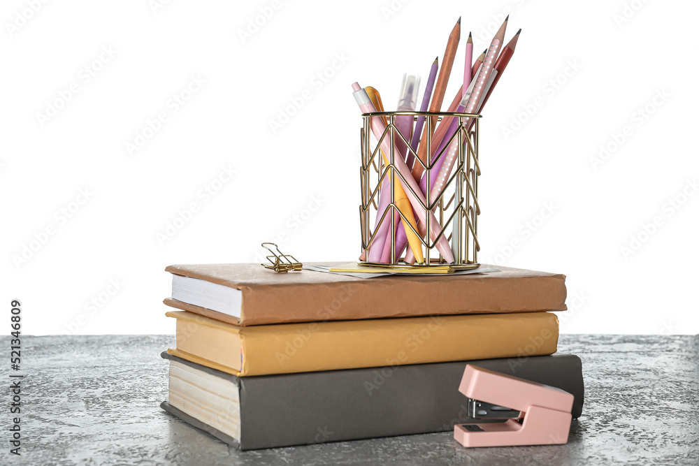 Cup with school stationery and books on table against white background