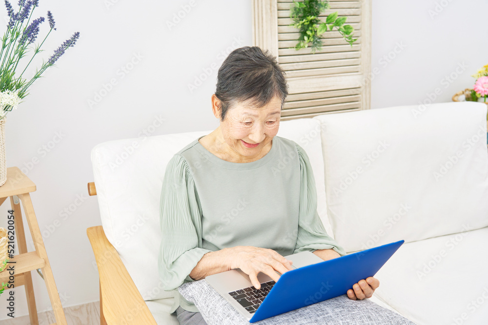 自宅でノートパソコンを使うシニア女性