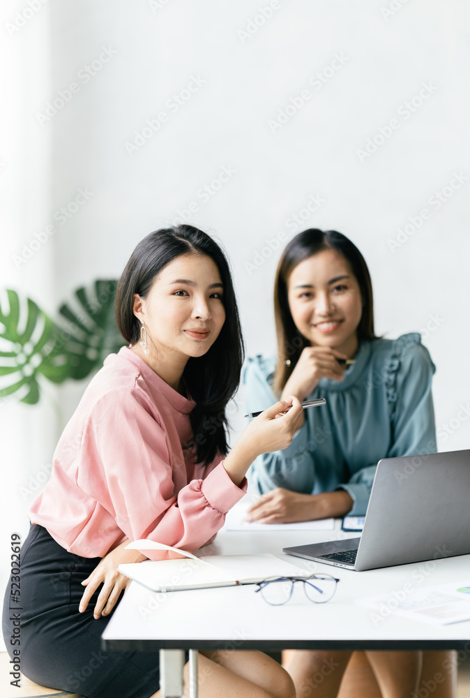 两位亚洲商务女性在会议室，两位美丽的商务女性开心而自信地微笑