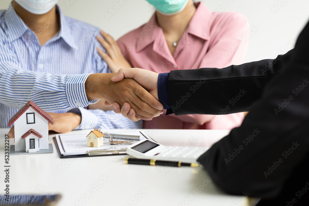 Real estate agents shake hands with customers after signing a legal home purchase agreement.