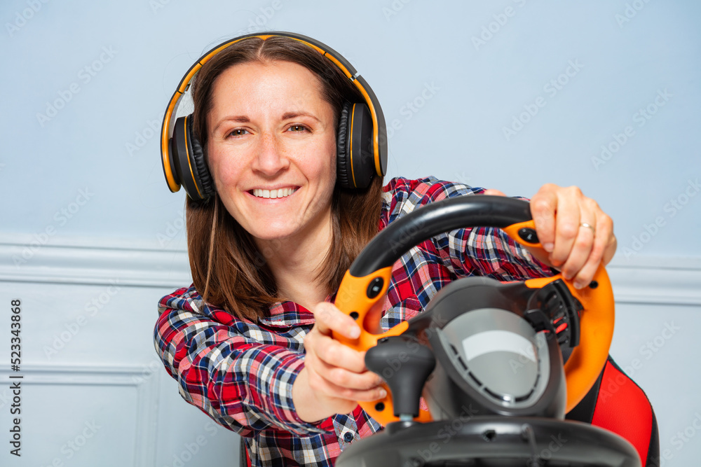 戴着耳机的女玩家用方向盘玩比赛游戏