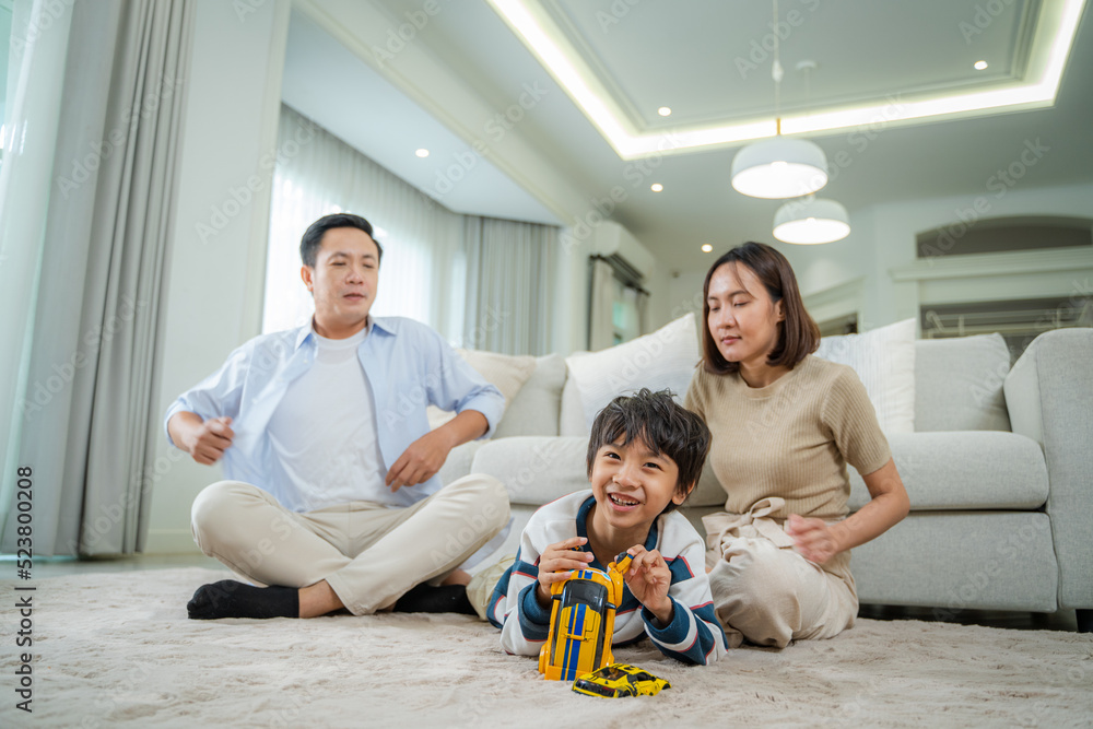 快乐的父母和儿子在客厅温暖的地板上玩耍，快乐的一家人享受周末