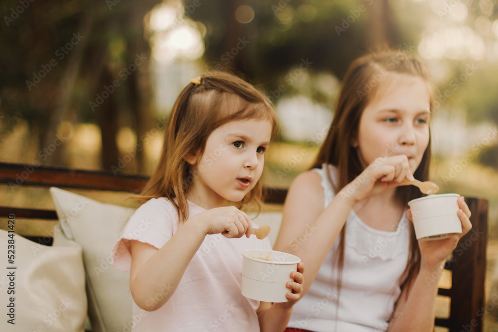 小女孩在夏日公园吃冰淇淋，看着镜头。可爱的宝宝在户外散步，享受