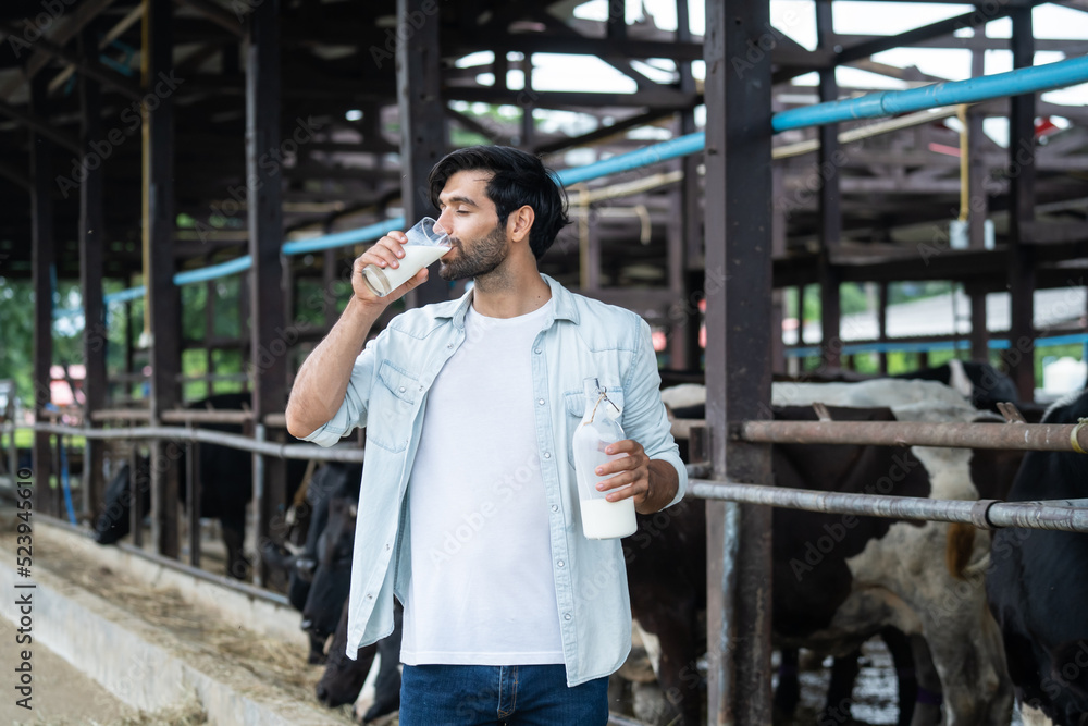高加索男性奶农在牛棚里拿着一瓶牛奶的肖像