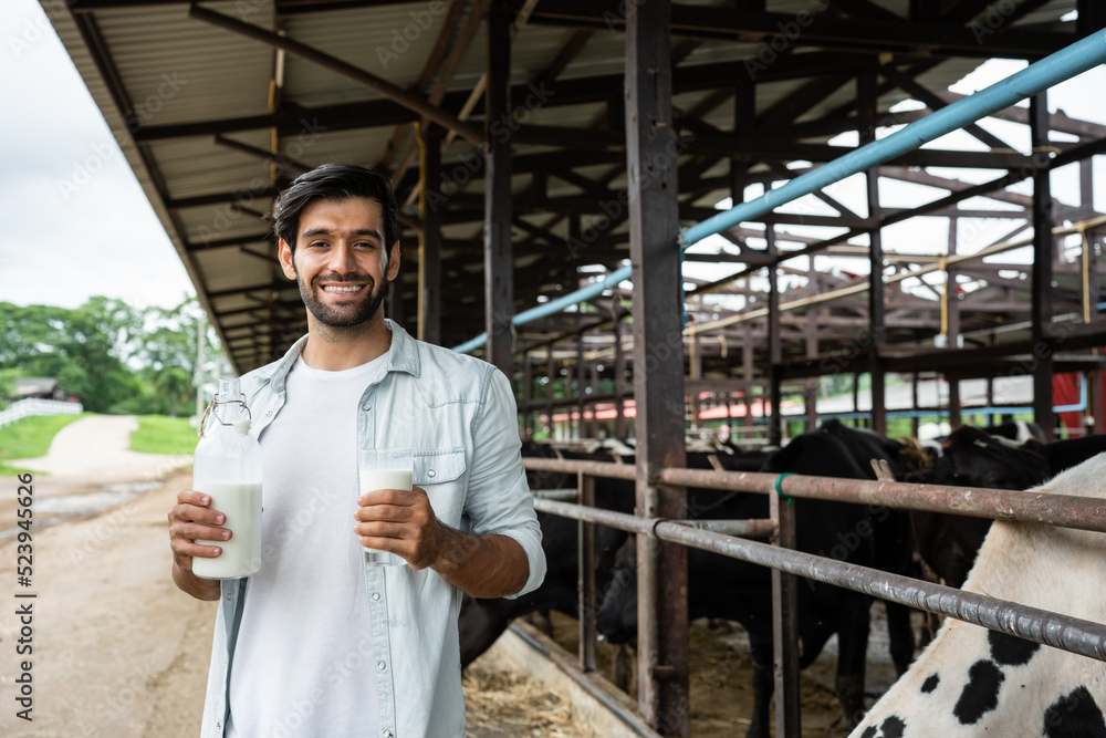 Portrait of Caucasian male dairy farmer hold bottle of milk in cowshed