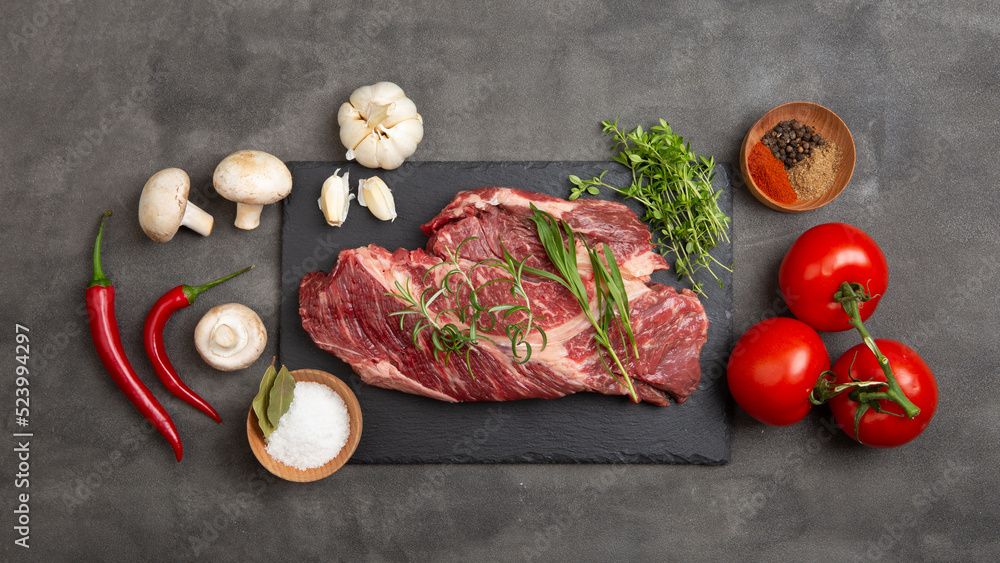 生牛排放在混凝土桌面上。健康食品概念。牛肉片和烹饪烧烤的香料