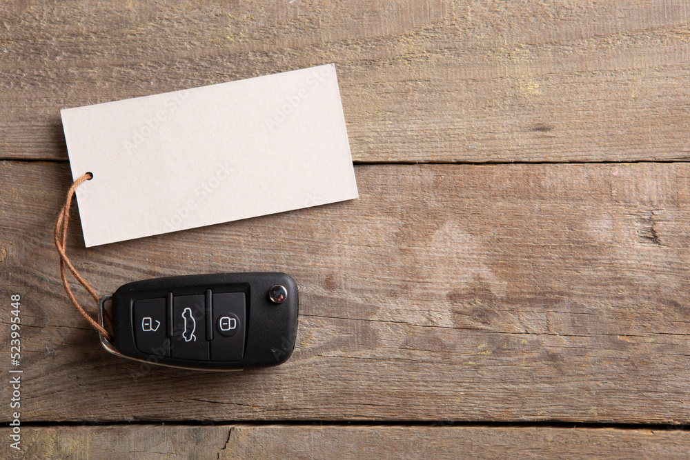 汽车保险或租赁概念。木质背景上有空白标签的车辆安全钥匙