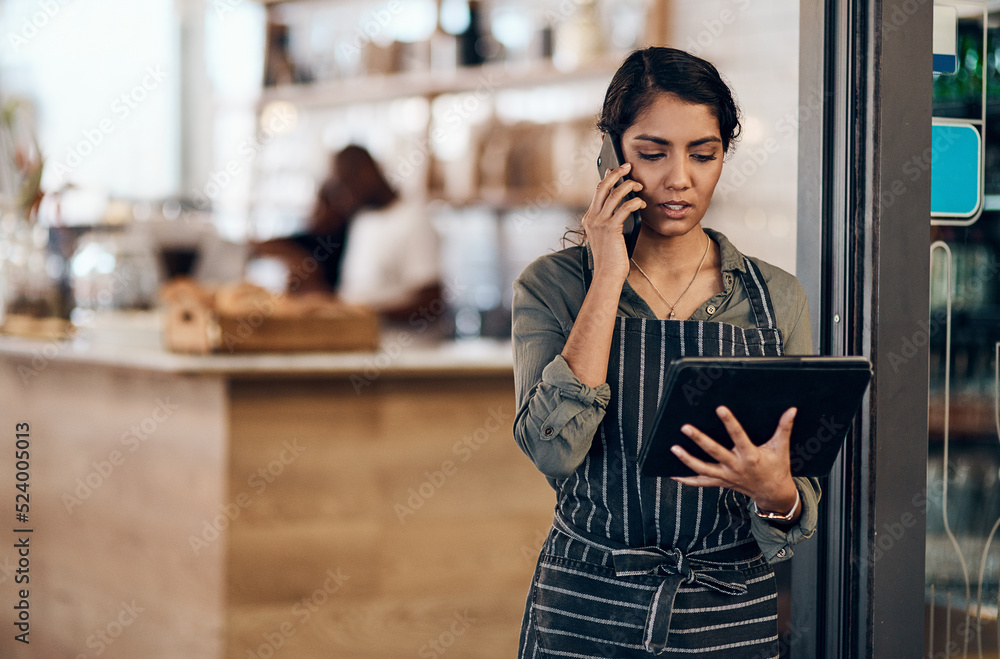 女咖啡馆老板在店里使用电话交谈、点餐和平板电脑阅读。严重
