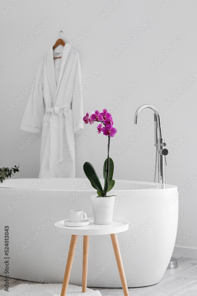 浴缸附近桌子上的兰花和杯子