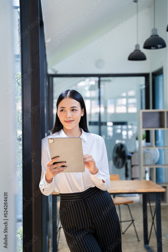 年轻迷人的亚洲女性上班族商务套装在现代办公室微笑