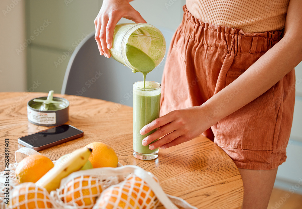 一位女性为排毒、饮用维生素和营养素而倾倒绿色健康奶昔的特写。女性