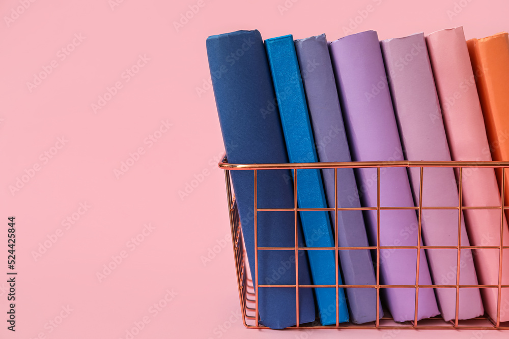 粉红色背景上有书的金属篮子