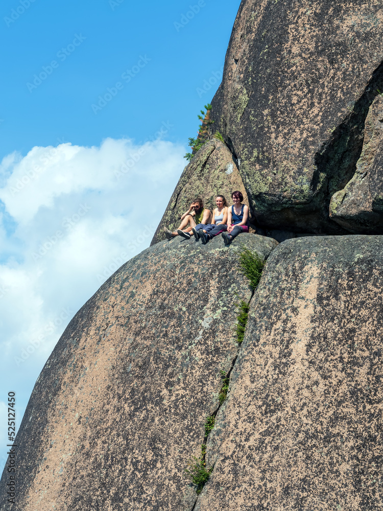 Three mountaineers are resting on a ledge of rock at a height of 315 feet. Hiking and alpinism. Outd