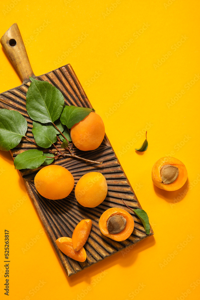 彩色背景上有成熟的杏子和叶子的木板
