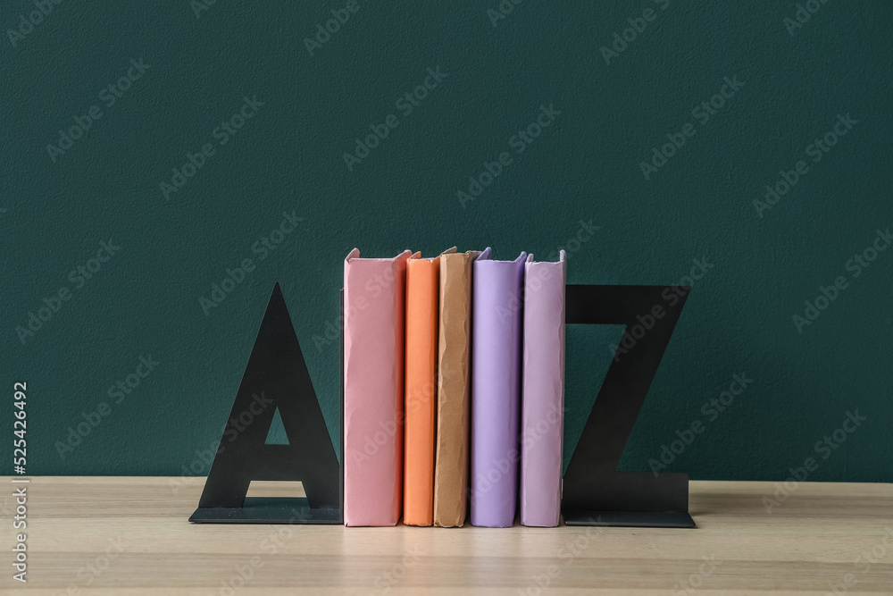 Stylish holder with books on table near green wall