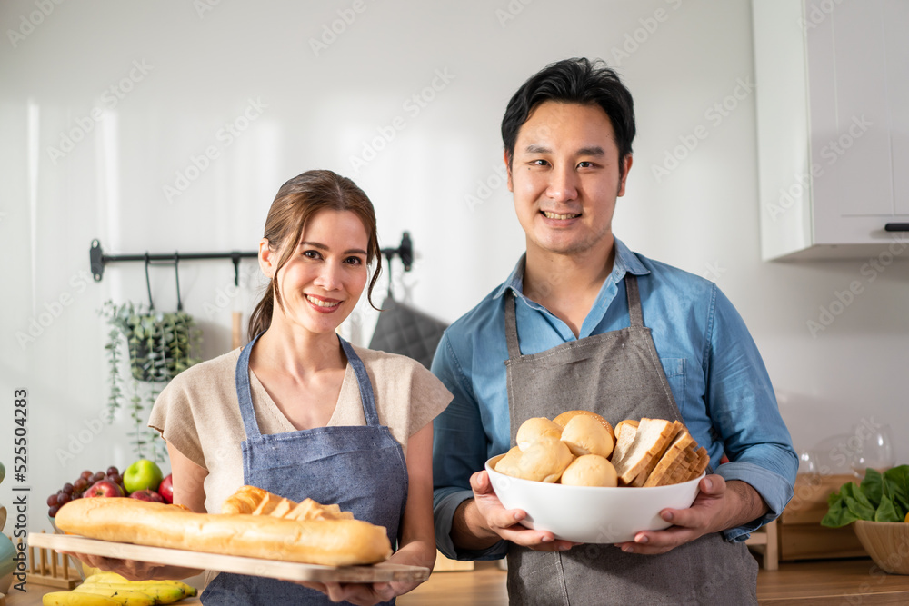 Portrait of Asian young couple hold a bowl of bread and look at camera.