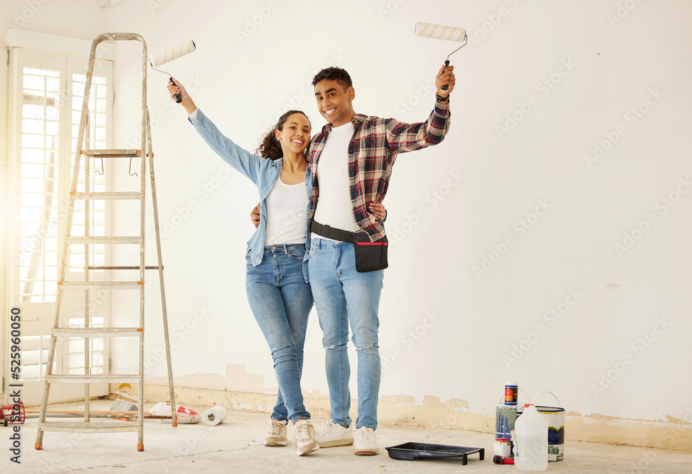 Portrait of happy couple painting the new living room in a home or apartment. Man and woman with pai