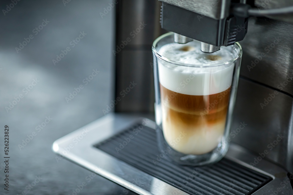 制作新鲜拿铁咖啡的浓缩咖啡机。将浓缩咖啡倒入新鲜蒸牛奶中