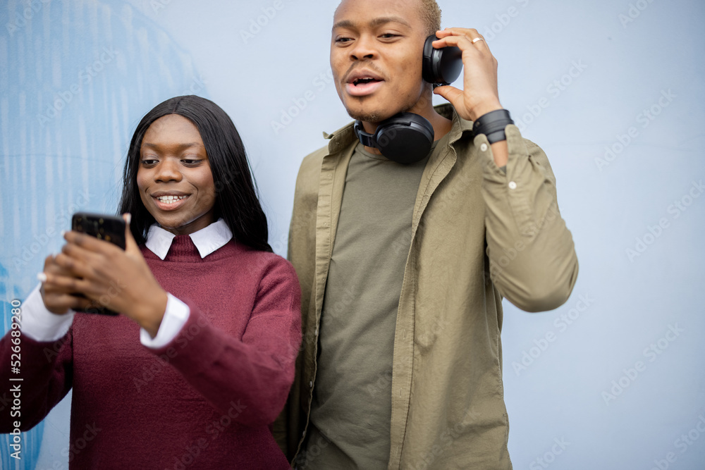 年轻的黑人夫妇在智能手机上自拍。微笑的女孩和严肃的男人。花钱的概念