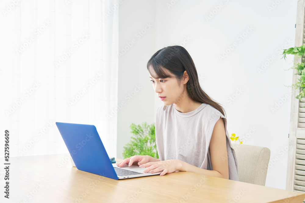 リビングでノートパソコンを心配そうに見る女性