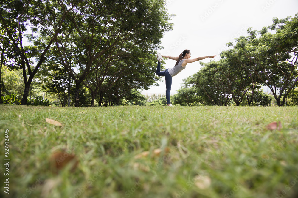 亚洲女性在公园里做瑜伽姿势。健康生活方式和户外生活的概念。