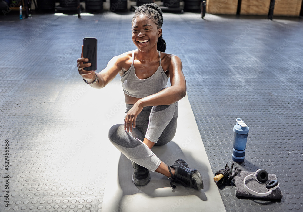 女子在健身房用手机自拍，健身前用智能手机视频通话