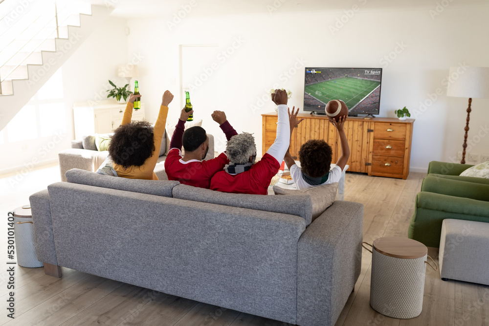 非裔美国人一家坐在沙发上用笔记本电脑看足球比赛
