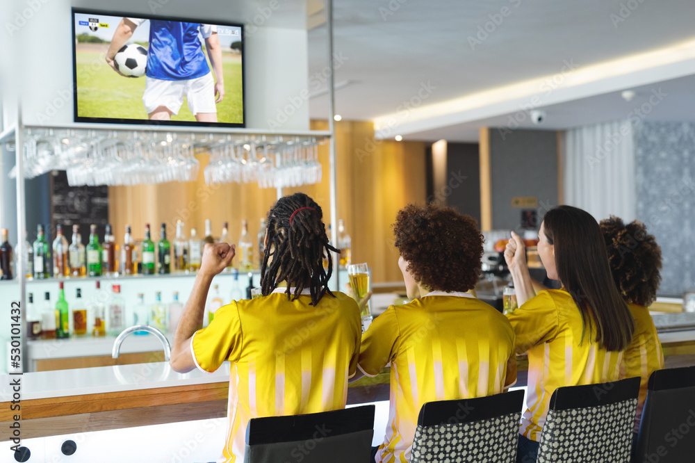 一群形形色色的朋友坐在酒吧里，喝啤酒，看足球比赛