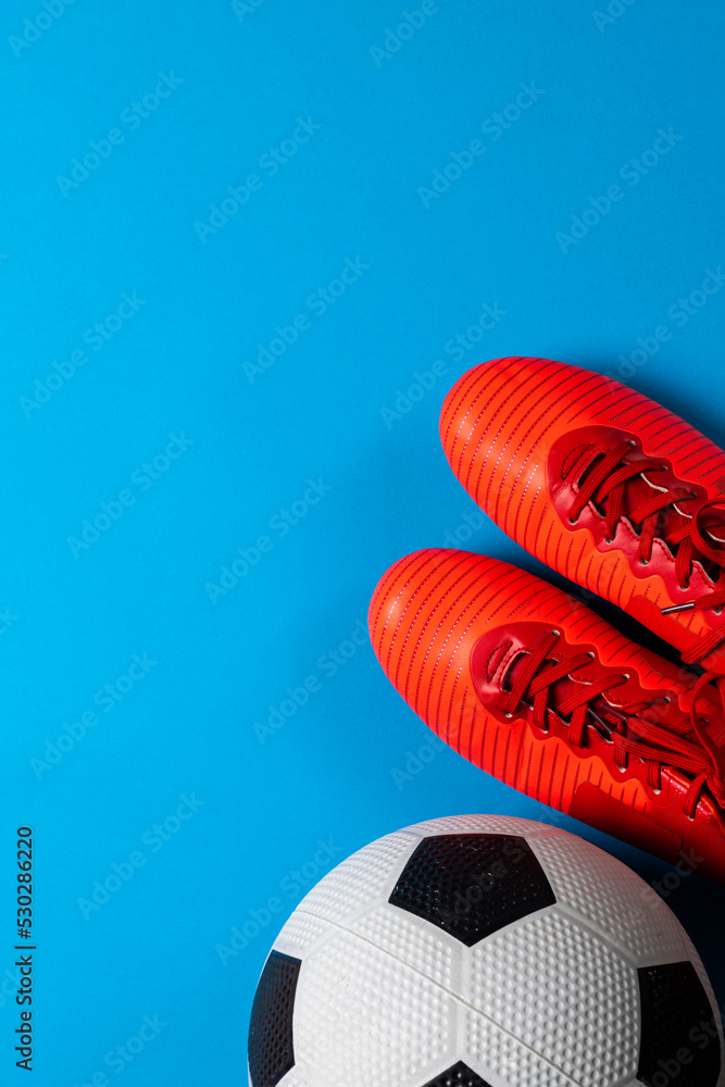 蓝色背景的足球和红色鞋子的构图，带有复制空间
