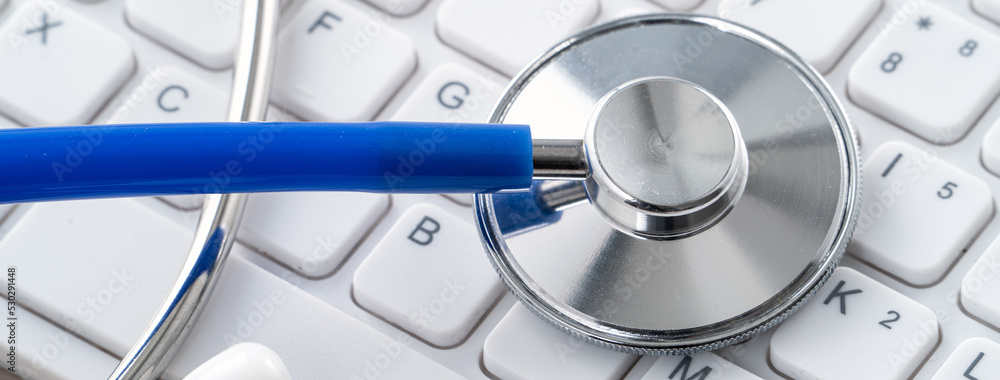 笔记本电脑键盘上的蓝色听诊器，医疗设计理念。