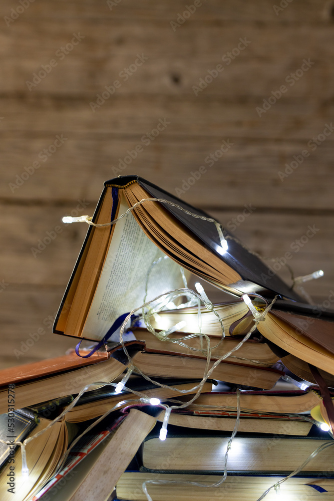 木制背景下童话般的灯光和一叠书的圣诞装饰图像