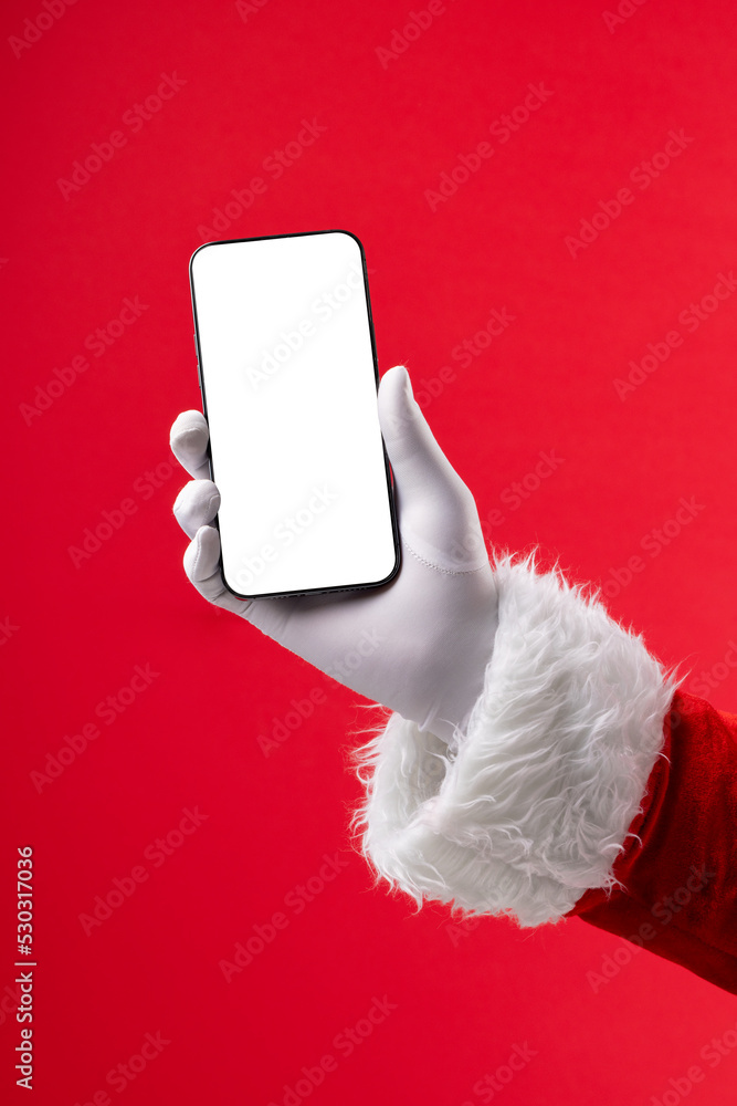 圣诞老人拿着智能手机的手的图像，屏幕空白，红底有复制空间