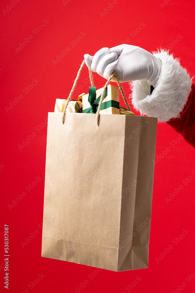 圣诞老人的手拿着红底圣诞礼物的纸袋