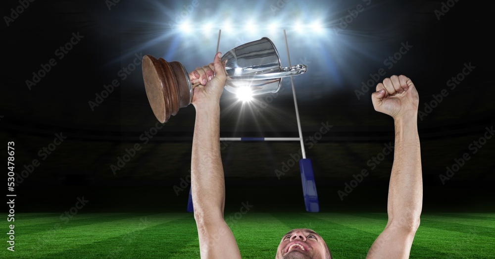男子橄榄球运动员庆祝胜利，在体育场橄榄球场上捧起奖杯的构成