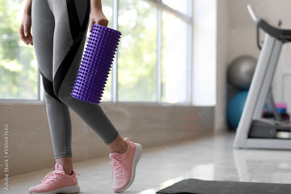 Young woman with purple foam roller in gym