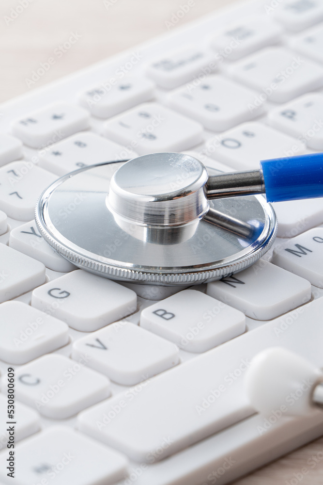 笔记本电脑键盘上的蓝色听诊器，医疗设计理念。