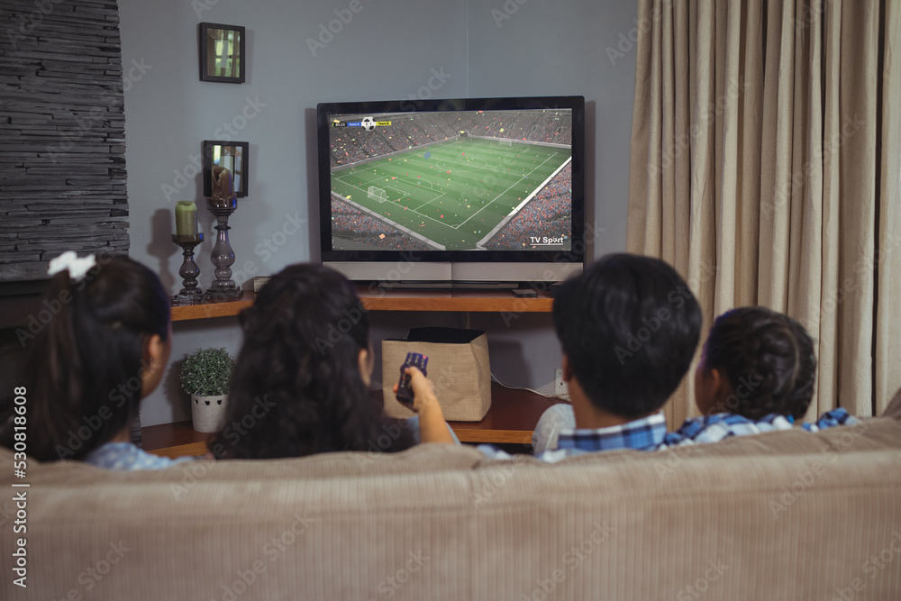 多样化的孩子在看电视，屏幕上有足球比赛