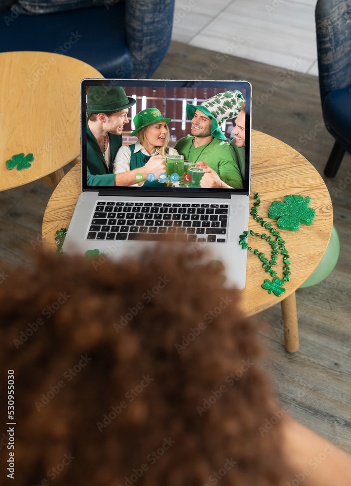 酒吧里的混血男子在笔记本电脑屏幕上给庆祝圣帕特里克节的朋友打视频电话