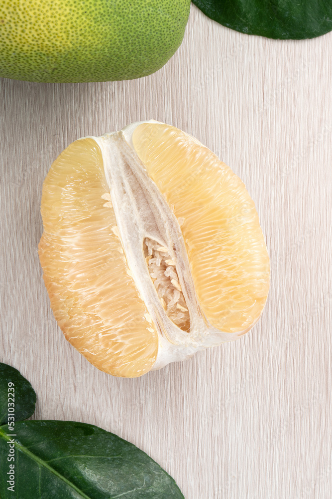 Fresh pomelo fruit on bright wooden table background.