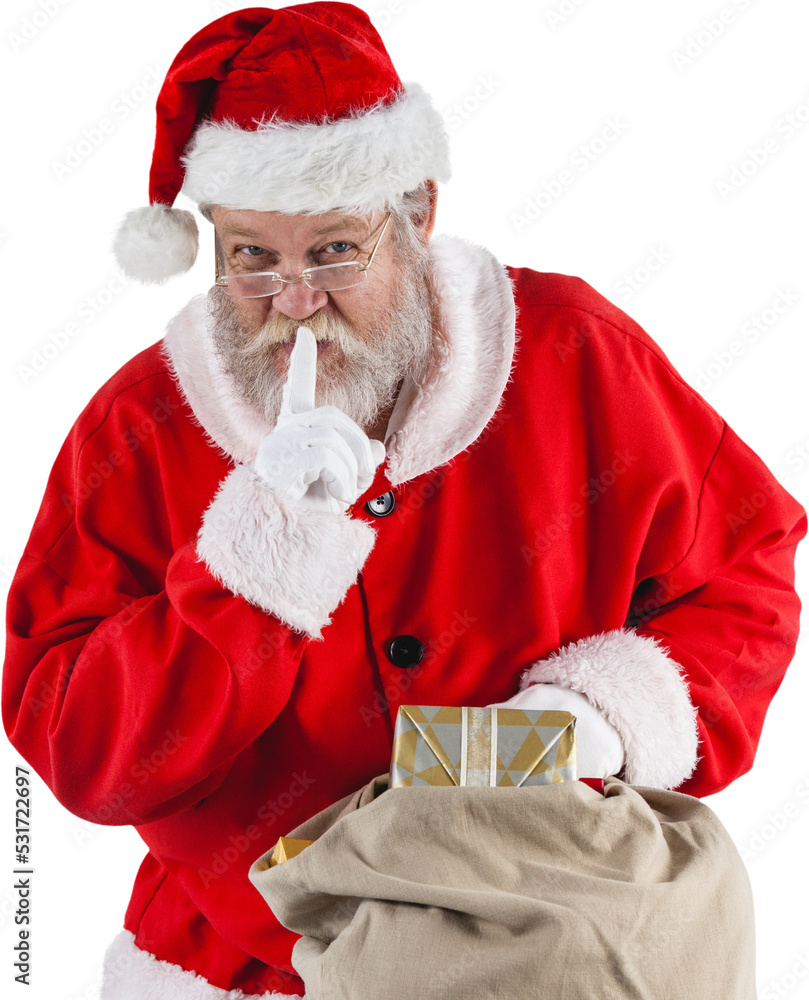 手指放在嘴唇上拿着圣诞礼物的圣诞老人的照片