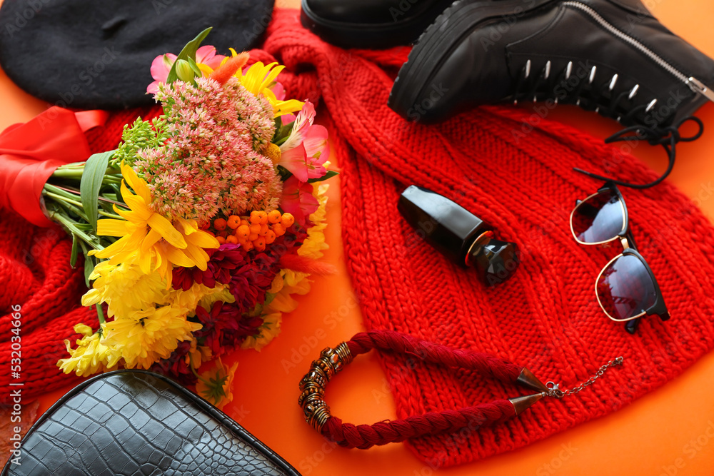 时尚的女性配饰、针织围巾、橙色背景的花束和秋叶