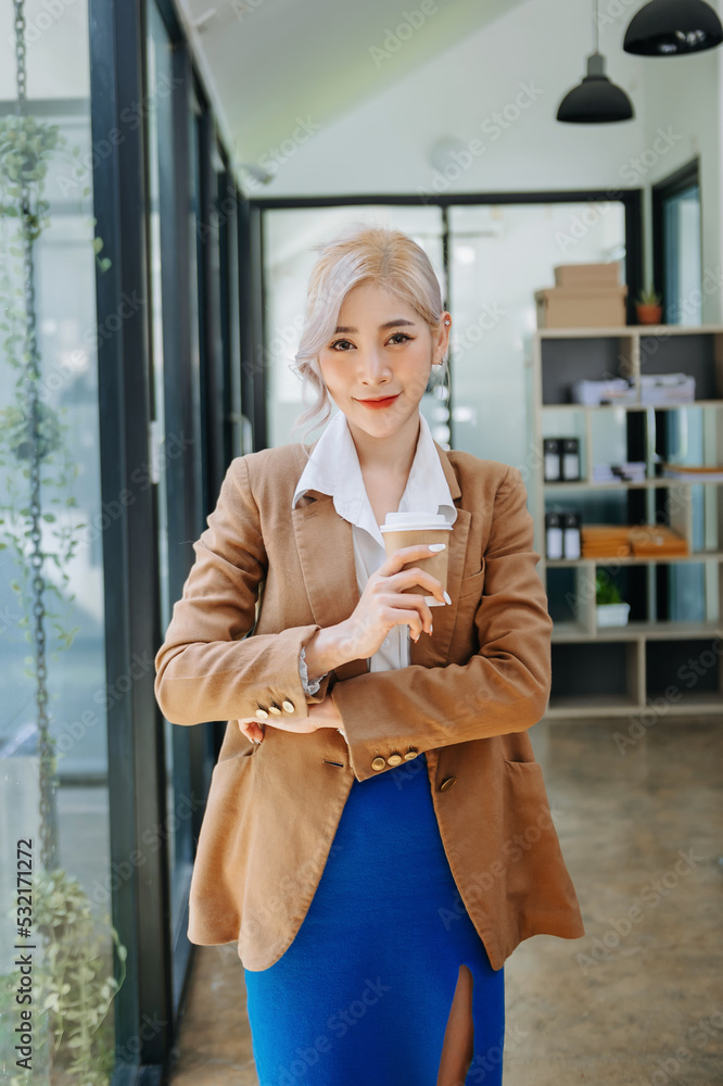 年轻迷人的亚洲女性上班族商务套装，在办公室对着镜头微笑。