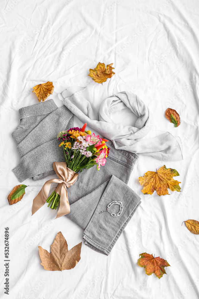 白色织物背景上的花朵与秋季服装、配饰和落叶的花束