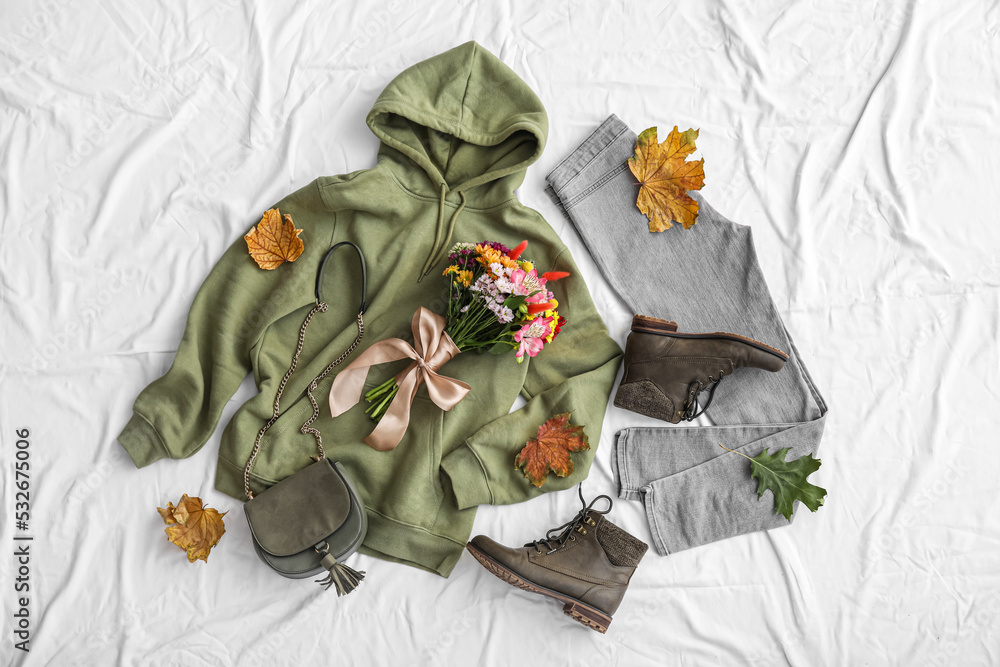 白色织物背景下的秋天衣服、袋子、鞋子和落叶的花束