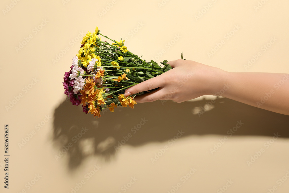 米色背景下的女性手和一束美丽的花