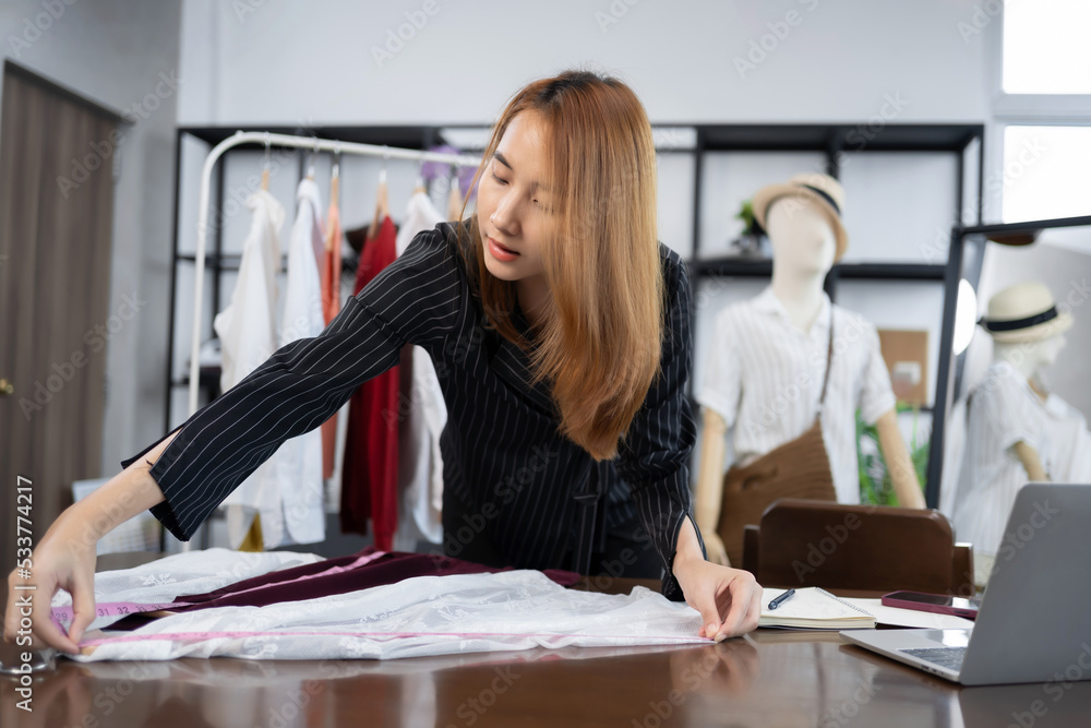 业主企业亚洲年轻女性时装设计师在展厅里为她的设计师工作。